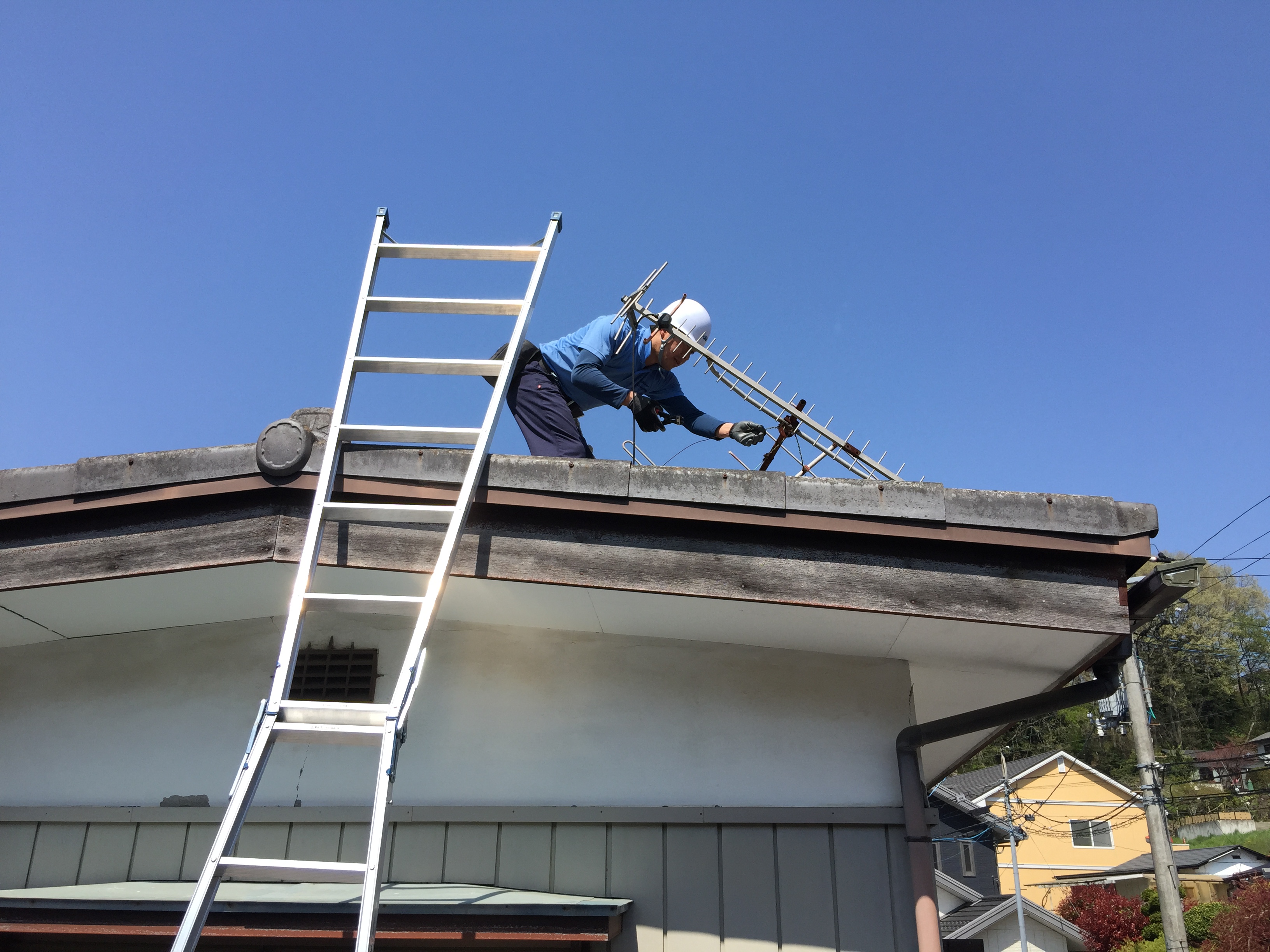 脚立で屋根に上りアンテナを撤去する